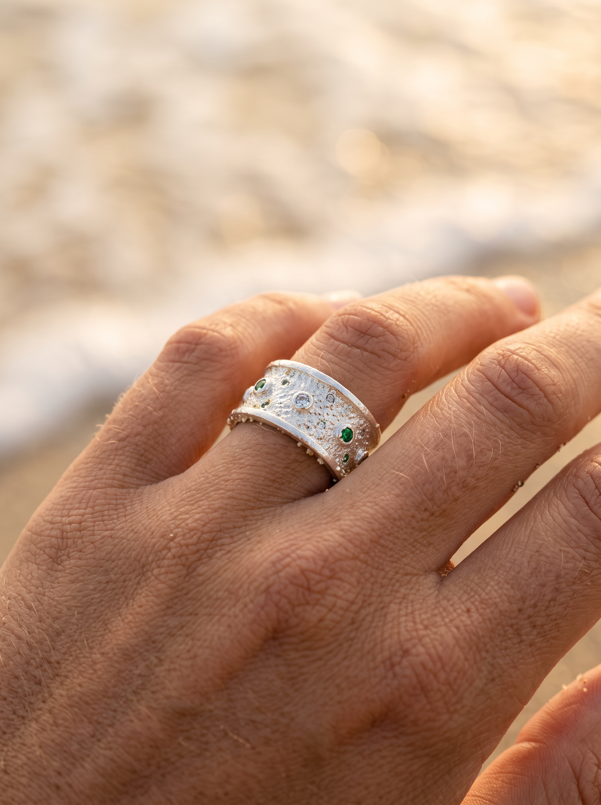 Anillo Polvo de Estrellas de plata con circones verdes en la mano, playa | Buono Joyas