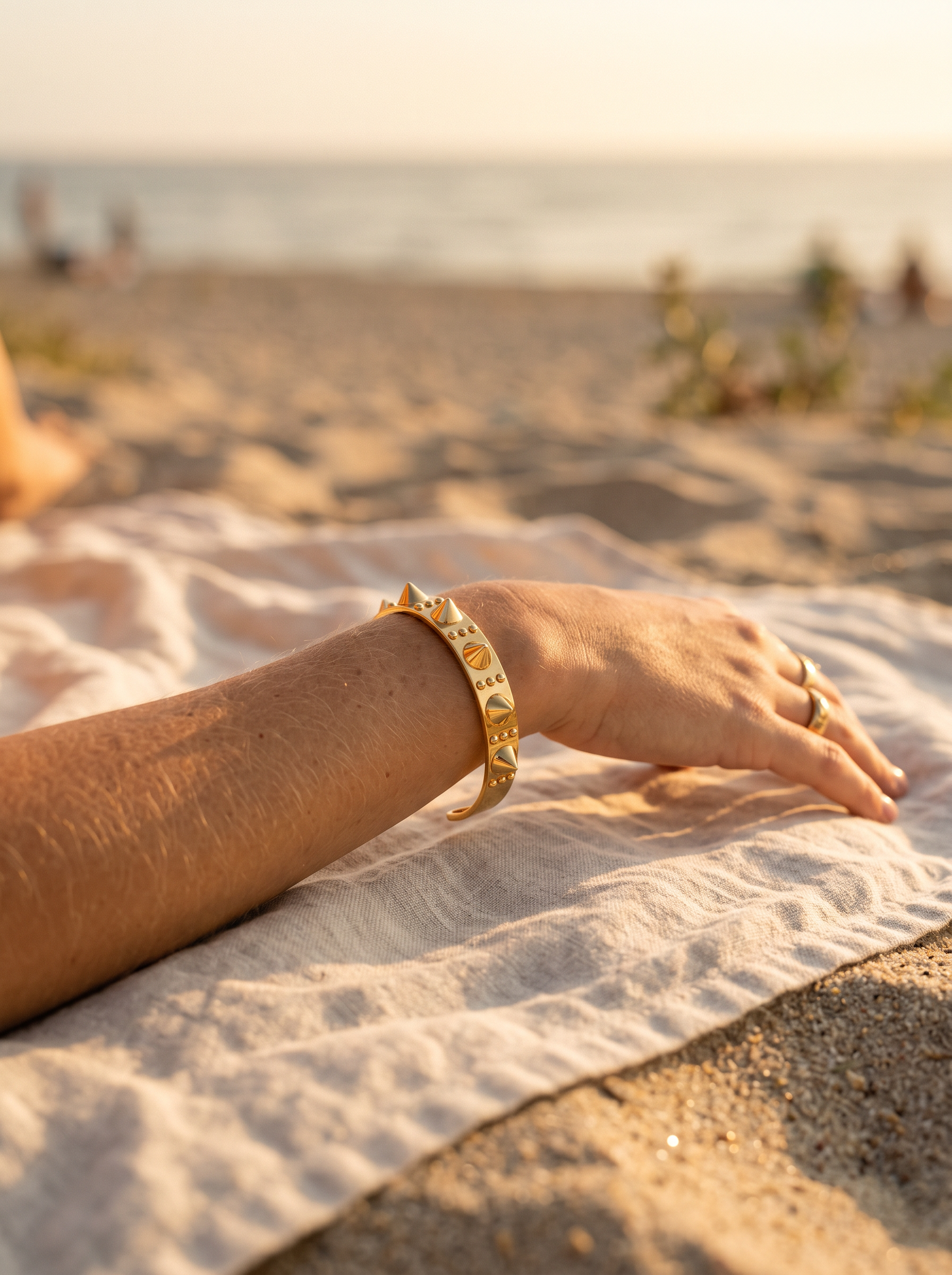 Brazalete Apex en el brazo sobre toalla de lino en la arena | Buono Joyas