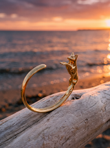 Brazalete Cuff Zorro Dorado sobre madera frente al mar al atardecer | Buono Joyas