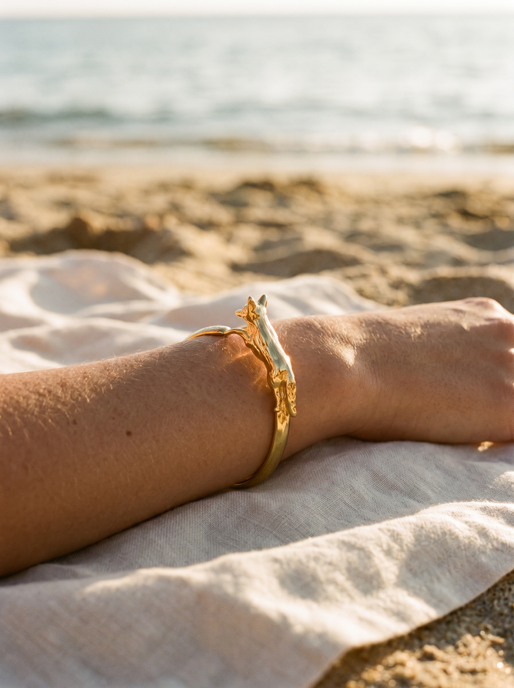 Brazalete Cuff Zorro Dorado en el brazo sobre toalla de lino | Buono Joyas