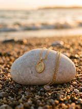 Cadena con Cruz sobre piedra de playa al atardecer | Buono Joyas