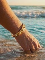 Brazalete Apex dorado con pinchos, muñeca en el agua | Buono Joyas
