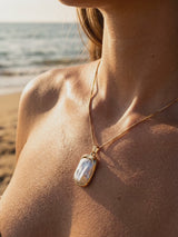 Collar Esencia con perla barroca en el escote, playa al atardecer | Buono Joyas